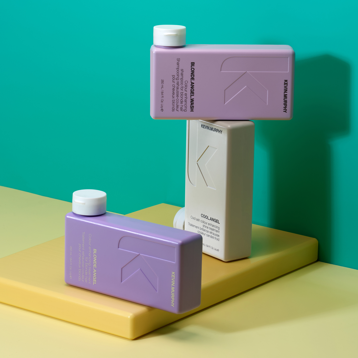 Kevin Murphy BLONDE.ANGEL.WASH and COOL.ANGEL bottles on color blocks against a teal backdrop.